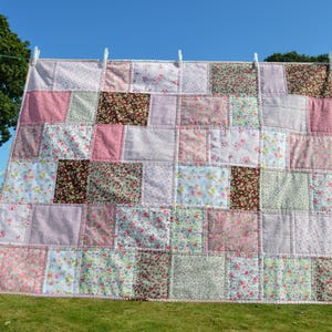 May include: A patchwork quilt featuring a range of floral patterns in shades of pink, brown, and white.