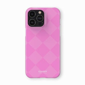 May include: A pink phone case with a diamond pattern and the word "CLASSY" printed on the back.