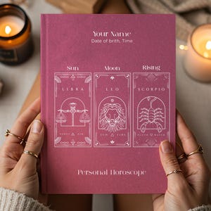 May include: A magenta hardback book titled Personal Horoscope with white line art illustrations of Libra, Leo, and Scorpio zodiac signs. The cover features text fields for Your Name, Date of birth, and Time, arranged in three vertical rectangular panels.