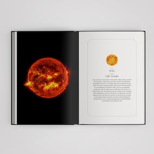 May include: An open book displaying a vibrant, glowing orange and red image of the Sun on the left page. The right page features a small circular icon of the Sun, the text Sun, Life Goals, and a paragraph explaining the Sun's role in astrology.