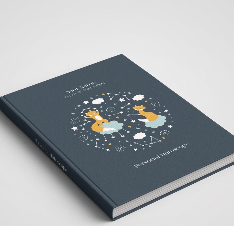 May include: A dark blue hardcover journal with a personalized name, date, and time. The cover features a whimsical illustration of two foxes on clouds surrounded by stars and constellations. The text "Personal Horoscope" is printed on the cover.