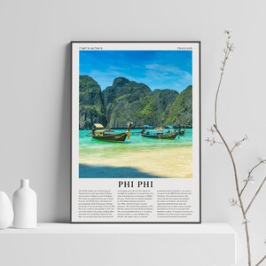 Może przedstawiać: Panoramiczne zdjęcie wyspy Phi Phi w Tajlandii. Na zdjęciu widać turkusowy ocean z dwoma łodziami długoogonowymi zakotwiczonymi w wodzie. Łodzie znajdują się przed bujną zieloną wyspą z imponującymi wapiennymi klifami. Tekst "PHI PHI" jest wydrukowany na czarnym tle w kolorze białym na dole zdjęcia.
