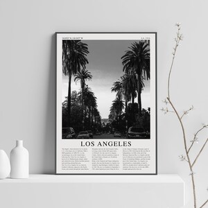 May include: Black and white photograph of palm trees lining a street in Los Angeles, California. The image includes the text "Los Angeles" and coordinates "34.0522&deg; N, 118.2437&deg; W".