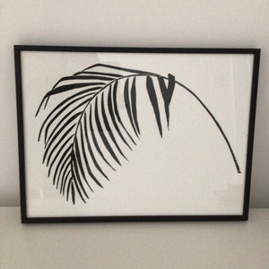 May include: Black and white framed print of a palm leaf silhouette.