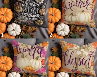 May include: Four decorative throw pillows with fall-themed designs. Pillows feature pumpkins and autumn leaves with phrases like "Happy Pumpkin Spice," "Gather," "Thankful," and "Blessed." Surrounding the pillows are orange and white pumpkins.