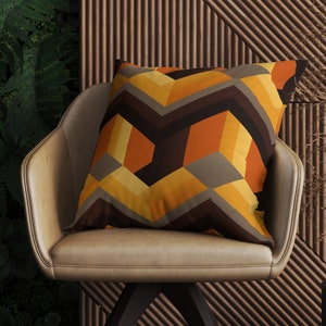 May include: A brown, orange, and yellow geometric patterned throw pillow on a brown leather chair.