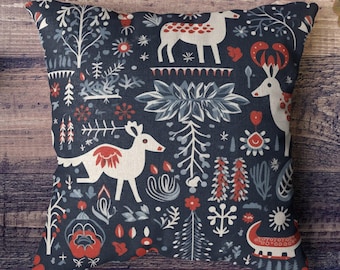 May include: A blue throw pillow with a white and red Scandinavian-style pattern featuring stylized deer, trees, and snowflakes.