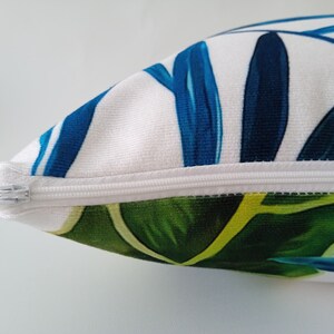May include: A white pillow with a zipper closure. The pillow has a blue and green tropical leaf pattern.