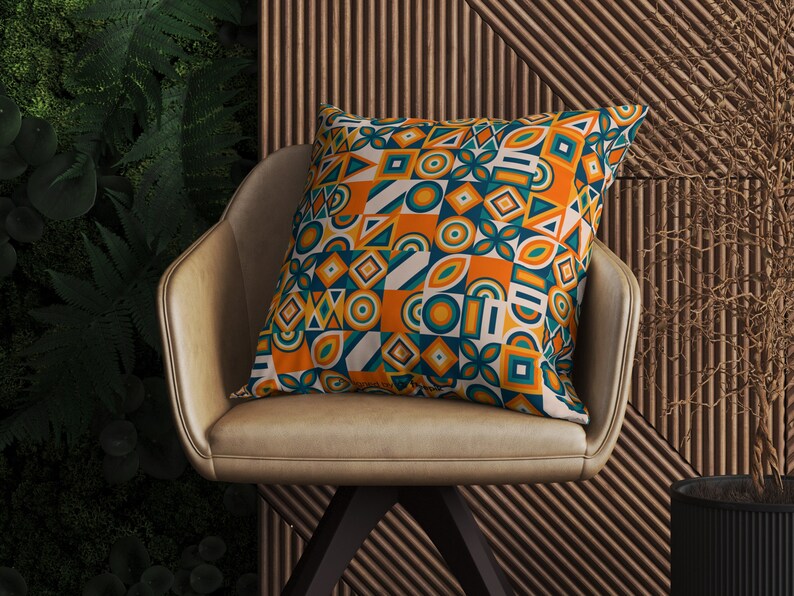 May include: A decorative throw pillow with a geometric pattern in shades of orange, teal, and white. The pillow is sitting on a brown leather chair.