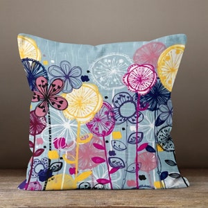 May include: A decorative throw pillow with a floral design. The pillow features a light blue background with colorful flowers in shades of pink, yellow, and blue. The flowers have a whimsical, hand-drawn style, adding a touch of artistic flair to the home decor.