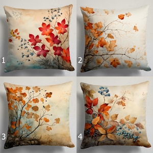 May include: Four square throw pillows with watercolor autumn designs. Pillows feature vibrant red, orange, and yellow leaves, branches, and berries against a soft, neutral background. Each pillow has a unique composition, perfect for seasonal home decor.