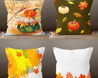 May include: Four decorative throw pillows with autumn themes. One pillow features a pumpkin stack with the text "Let em Blow". Another has pumpkins and leaves on a dark green background. The third has yellow and orange brushstrokes with leaves. The last has a white background with leaves.
