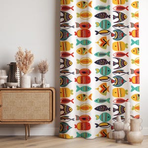 May include: White curtain with a repeating pattern of colorful, stylized fish. The fish are in rows and feature various colors including red, yellow, blue, and black. The curtain is likely made of fabric and is hanging in front of a window.
