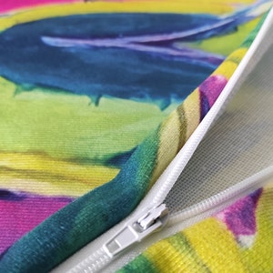 May include: A colorful pillow with a zipper closure. The pillow has a green, blue, yellow, and pink abstract design.