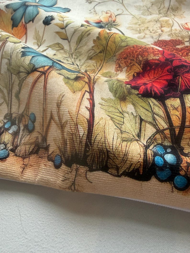 May include: Close-up of a fabric with a detailed botanical print. The design features large red and blue flowers, green leaves, and various plant elements. The color palette includes beige, brown, red, and blue tones, creating a vintage aesthetic.