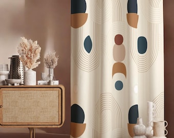 Puede incluir: Cortina de color crema con un patrón geométrico repetido de formas azul marino, marrón y óxido y líneas curvas. La cortina cuelga frente a una pared de tonos neutros. Jarrones decorativos y un mueble de madera en el fondo.