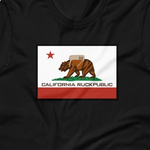 May include: Black t-shirt with a white and red California flag design. The flag features a brown bear with a backpack and the text "CALIFORNIA RUCKPUBLIC".