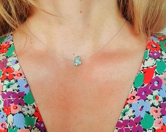May include: A delicate silver chain necklace with a small, irregular, light blue gemstone pendant.