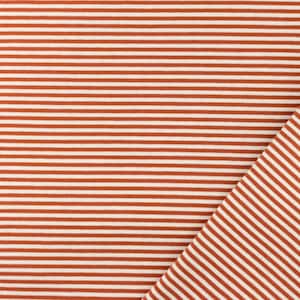 Op de afbeelding: Close-up van een stof met een herhalend patroon van horizontale strepen. De strepen wisselen af tussen een warme, roodbruine kleur en wit. Een deel van de stof is diagonaal gevouwen.