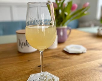 Może przedstawiać: Przezroczysty kieliszek z personalizowanym napisem "Mama" wypełniony jasnożółtym napojem. Kieliszek stoi na białym podkładce z napisem "Gonn' glas" złotymi literami.