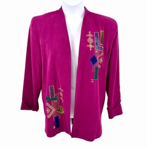 May include: A magenta open-front jacket with long sleeves and decorative geometric embroidery. The embroidery features squares, rectangles, and other shapes in various colors, including gold, blue, green, and teal. The jacket is displayed on a white mannequin.