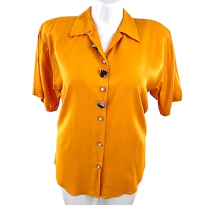 May include: A bright orange short-sleeved button-down shirt with floral buttons.