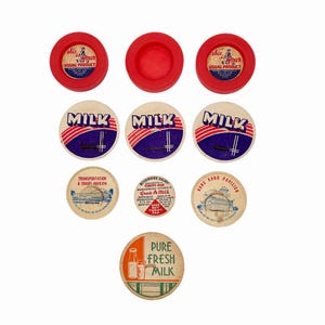May include: A collection of vintage milk bottle caps. The caps feature various designs, including the words "MILK," "PURE FRESH MILK," and advertising for "Riverside Dairy" and "Hong Kong Pavilion." Some caps are red, others are white and tan.