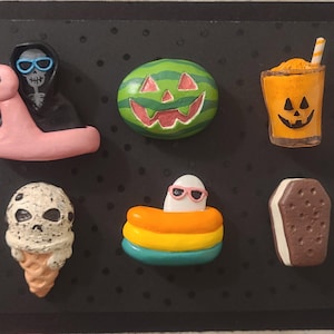 May include: A collection of novelty magnets with a Halloween and summer theme. Includes a flamingo pool float with a skeleton, a carved watermelon, a jack-o'-lantern drink, an ice cream cone, a ghost in a pool float, and an ice cream sandwich.