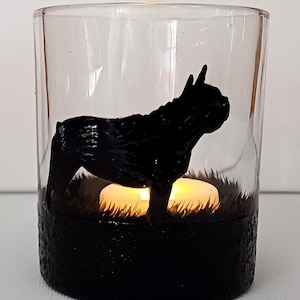 May include: A glass candle holder with a black silhouette of a French Bulldog. The holder has a black base and a clear glass top. A small white candle is inside the holder.