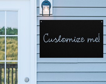 May include: A black metal sign with white text that reads "Customize me!" hanging on a light blue siding wall.