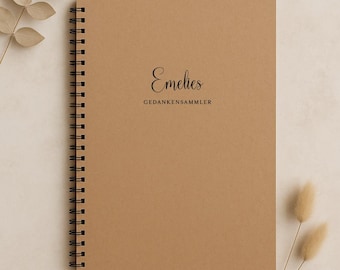 May include: A spiral-bound notebook with a kraft paper cover. The cover features the name "Emelies" in elegant script above the words "GEDANKENSAMMLER". The notebook is surrounded by dried plants.