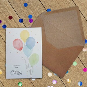 May include: A white card with a watercolor illustration of four colorful balloons. The card says "Einladung zum Geburtstag" which translates to "Invitation to Birthday" in English.