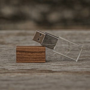 May include: A wooden USB drive with a clear acrylic case. The drive is lying on a wooden surface.