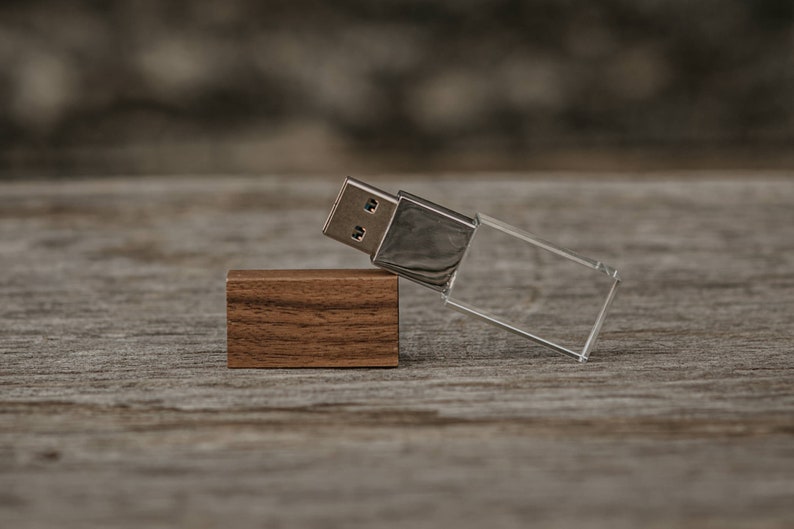 May include: A wooden USB drive with a clear acrylic case. The drive is lying on a wooden surface.