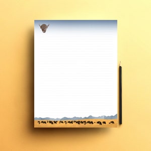 Op de afbeelding: Gelijnd notitieblok met een buffelillustratie bovenaan en een kudde buffels onderaan. Een zwarte potlood ligt aan de rechterkant. De achtergrond is een blauw-witte gradiënt.
