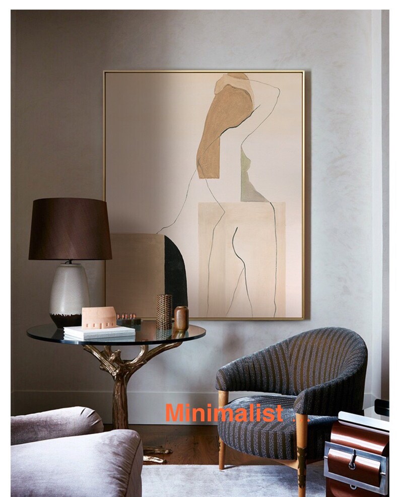 May include: Abstract art print featuring a nude figure in shades of brown, beige, and green. The print is framed in a gold frame and hangs on a wall in a living room setting.