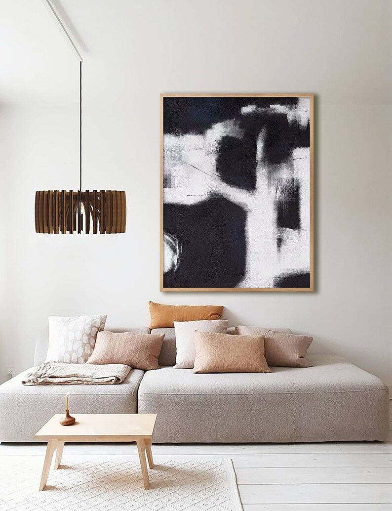 May include: A modern living room with a white couch, a wooden coffee table, and a black and white abstract painting hanging on the wall. A wooden pendant light hangs from the ceiling.