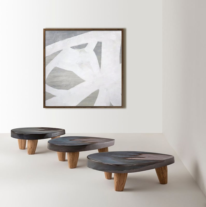 May include: Three dark gray ceramic pedestals with wooden legs. The pedestals are arranged in a row from left to right. The pedestals are on a white surface.