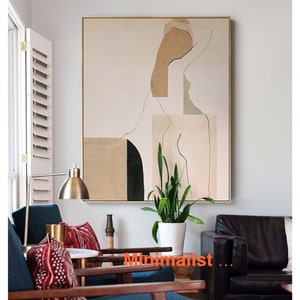 May include: Abstract art print featuring a minimalist line drawing of a person with geometric shapes in beige, green, and black. The print is framed in gold and displayed on a wall in a living room setting.