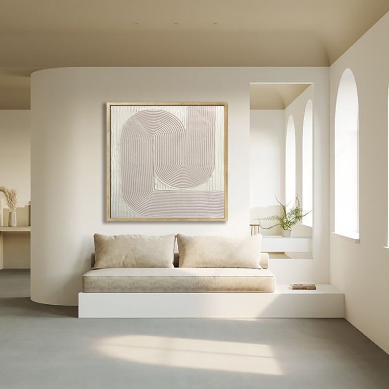 Peut inclure: Une &oelig;uvre d'art murale g&eacute;om&eacute;trique abstraite blanche et rose p&acirc;le avec un cadre en bois. L'&oelig;uvre d'art est accroch&eacute;e &agrave; un mur blanc au-dessus d'un canap&eacute; beige.