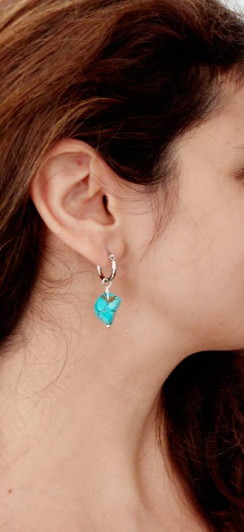 May include: A silver hoop earring with a turquoise stone pendant. The stone is a light blue color with brown veins.