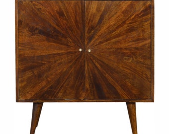 May include: A dark brown wooden cabinet with two doors and a sunburst design. The cabinet has four legs and brass hardware.