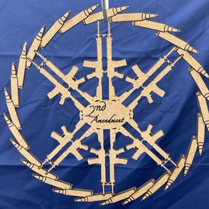 May include: A wooden snowflake ornament with a 2nd Amendment inscription in the center. The snowflake is made up of six stylized rifles, with bullet casings forming the outer ring.