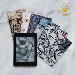 May include: Five different fabric covers for an e-reader. The covers are in various patterns, including floral, geometric, and animal print. The covers are all laid out on a white marble surface. The text "Forever Unique Craft" is visible in the top right corner of the image.