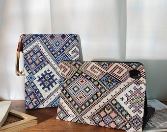 May include: Two tablet cases with colorful geometric patterns. One case is upright with a brown leather handle, the other is open, displaying the tablet. The cases feature a mix of blue, pink, yellow, and black designs.