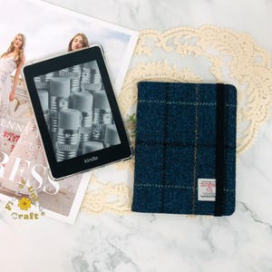 May include: A blue and brown tweed Kindle cover with a black elastic closure. The cover has a small label with the text "Harris Tweed" on it.