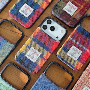 May include: A selection of phone cases with a tartan design in shades of red, blue, and yellow. Each case has a black border and a small white label. The cases are made from a textured fabric. The cases are designed to fit a smartphone.