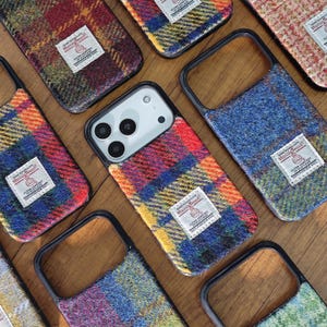 Könnte beinhalten: Eine Sammlung farbenfroher Handyhüllen mit einem karierten Tweed-Design. Die Hüllen weisen eine Vielzahl von Farben auf, darunter Rot, Blau, Gelb und Grün. Jede Hülle hat ein kleines weißes Etikett mit Text.