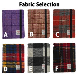 May include: Image shows six fabric samples labeled A through F. Each sample is a rectangular notebook cover with a black elastic band. The covers feature various plaid and tweed patterns in colors like purple, red, and black. The text "Fabric Selection" is at the top.
