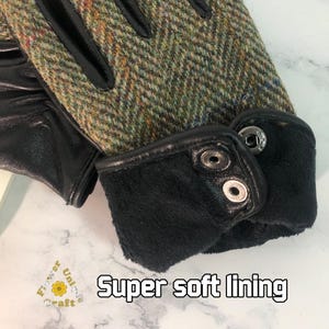 Op de afbeelding: Close-up van een paar handschoenen met een tweed bovenkant en een zwarte leren palm. De handschoenen hebben een zwarte fleece voering en een knoopsluiting.